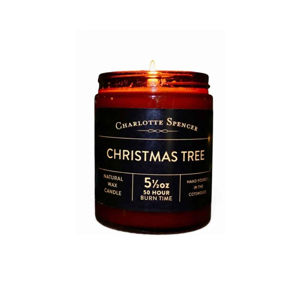 A Christmas Tree fragranced candle in an amber glass jar with black label.