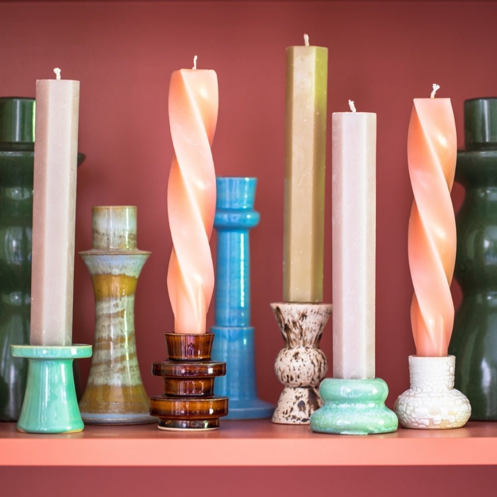 Ceramic candlesticks with coloured candles on a coral painted shelf.